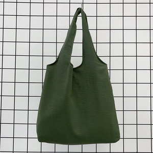 Close-up of deep green canvas tote bag texture hanging on black metal grid
