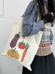 Dettaglio della borsa tote in tela con stampa vegetale che mostra trama e tracolla sulla spalla