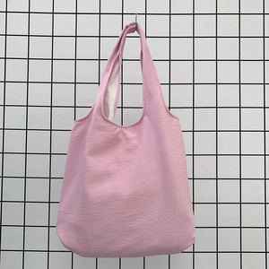 Detail view of pink tote bag showing ripple texture fabric and wide shoulder strap