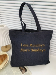 Detail of dark blue denim tote bag with yellow slogan on white window background