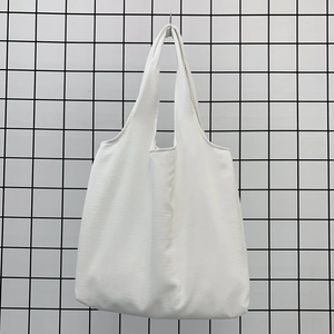 Close-up of white canvas tote bag showing fine woven fabric texture and wide handle