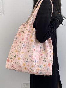 Détails de broderie florale sur un sac cabas en toile rose porté par un mannequin