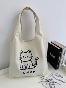 Détail d'un sac cabas en toile beige avec imprimé chat et large bandoulière