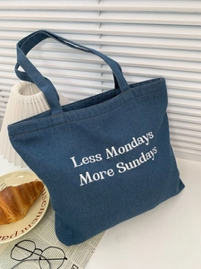 Detail of a dark blue denim tote bag with Less Mondays More Sundays print text