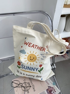 Dettaglio della borsa tote in tela con stampa sole su una sedia trasparente con accessori