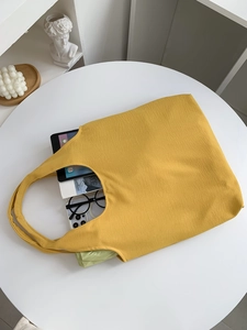 Detail of a bright yellow canvas tote bag showing its large capacity for daily items