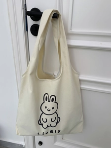 Détail du sac cabas en toile crème avec motif lapin et texte Lively sur poignée de porte