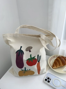 Dettaglio borsa shopper in tela bianca con stampe di verdure e ampi manici a spalla