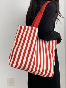 Detail of red and white striped canvas tote bag showing its large capacity and wide shoulder strap
