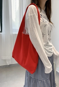 Detail of red canvas tote bag shoulder strap and fabric texture on female model