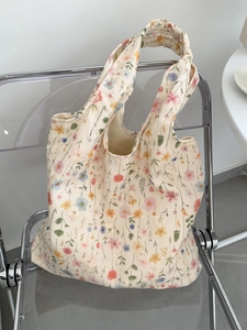 Détail d'un sac cabas en toile brodée à fleurs suspendu sur une chaise moderne
