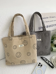 Detail of corduroy tote bags with smiley face patterns and brand label in a lifestyle setting