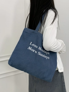 Detail of blue denim tote bag with Less Mondays More Sundays embroidery and thick texture