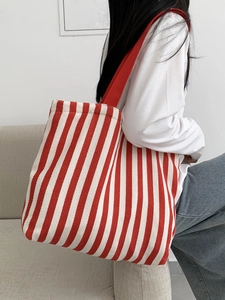 Detail of red and white striped canvas tote bag with vibrant red woven shoulder strap