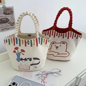 Detail of cartoon canvas bucket bags featuring woven rope handles and magnetic snap closure