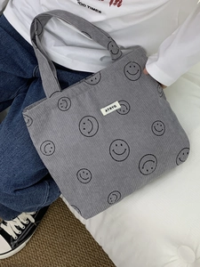 Detail of grey corduroy tote bag with smile patterns and embroidered ATRYG logo label