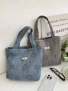 Close-up of corduroy tote bags in blue and dark grey with smiley face patterns