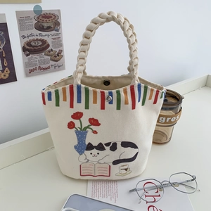 Detailed view of canvas bucket bag featuring cat illustration and braided handles
