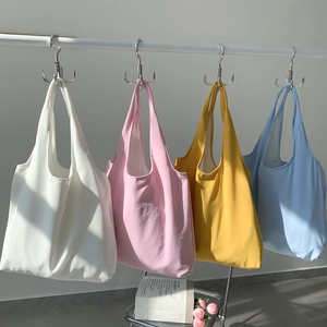 Detailed view of four colorful minimalist canvas tote bags in pastel shades on a clean wall