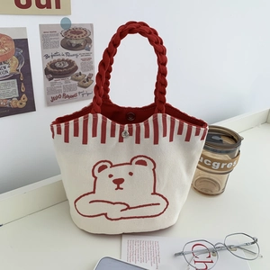 Close-up of canvas bucket bag featuring red woven handles and cute bear print