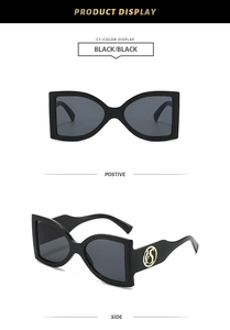 Detail view of large black square sunglasses featuring a golden hollow circular temple hinge