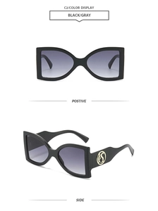 Detail view of oversized butterfly sunglasses with black frame and golden logo temple