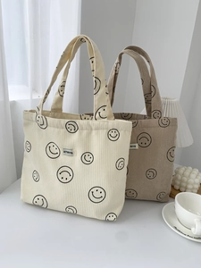 Detailed view of corduroy tote bags with smiley patterns and a woven logo label