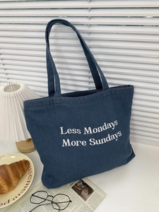 Detail of dark blue denim tote bag featuring white Less Mondays More Sundays embroidery