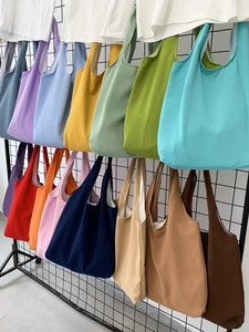 Colorful canvas tote bags in various colors hanging on a retail display grid rack