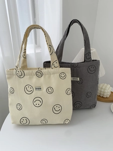 Detail view of corduroy tote bags with smiley prints and woven brand labels