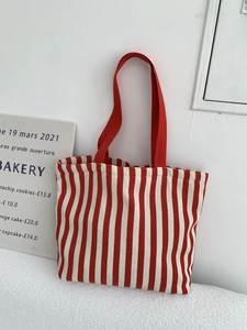 Close-up of red and white striped canvas tote bag with red shoulder straps in cozy setting