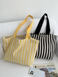 Detail view of striped canvas tote bags in yellow and black on a white textured sofa