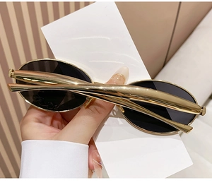 Detail of oval black lenses and sleek gold metal temples on fashion sunglasses