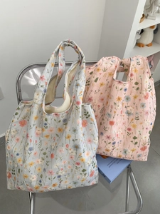 Gros plan sur la broderie florale des sacs cabas en toile bleu clair et rose pastel