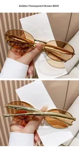 Detail view of oval golden metal sunglasses with transparent brown lenses and folding frame