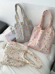 Détail de trois sacs cabas en toile brodés de fleurs en bleu, rose et blanc cassé