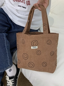Detailed texture of brown corduroy tote bag featuring smiley prints and ATRYG label