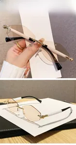 Détail de lunettes de soleil sans monture à verres marrons et branches dorées