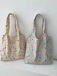 Détail de la broderie florale sur des sacs cabas en toile de coton blanc et bleu