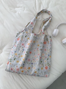 Détail de la broderie florale sur un sac cabas en toile bleu clair à longues anses