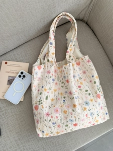 Détail de la broderie florale sur un sac cabas en toile crème posé sur un canapé gris