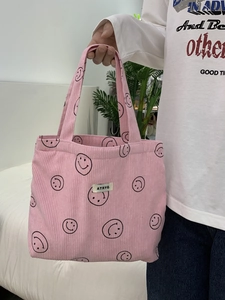 Pink corduroy tote bag detail with black smiley face prints and ATRYG woven label