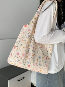Détail d'un sac cabas en toile fleurie montrant la large bandoulière et le motif floral