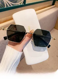 Detail of square gold metal sunglasses with dark lenses and a branded white storage box
