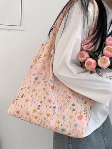 Sac fourre-tout en toile à fleurs avec broderie porté par un mannequin pour un look décontracté