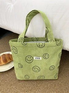 Detail of light green corduroy tote bag with black smile patterns and white fabric label