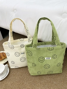 Detail of corduroy tote bags showing soft ribbed texture and cute smiley face embroidery