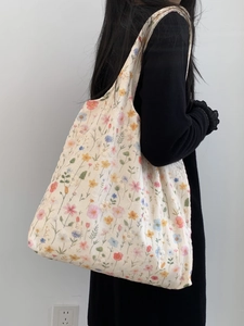 Sac fourre-tout en toile à broderie florale porté à l'épaule, vue latérale sur modèle
