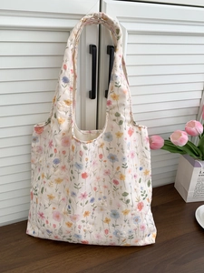 Gros plan détaillé d'un sac cabas en toile crème avec des motifs floraux brodés colorés