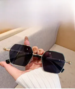 Detail of square gold metal sunglasses with dark grey lenses and spherical frame hinges